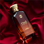 A sleek dark amber glass bottle of ajmal oud on the rocks eau de parfum with golden ribbed cap and smoky oud notes