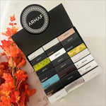 The Armaf Discovery Set - Premium Luxury Fragrance (7ML x 24 PCS) Long-Lasting Fragrance for Men & Women presents a beautifully organized display of miniature perfumes surrounded by autumn leaves. This vibrant travel perfume set by Armaf is perfect for gifting and personal use, emphasizing its new essence.