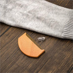 A wooden clothes fabric shaver with fine metal teeth and a smooth light brown finish for fabric shaver lint removal