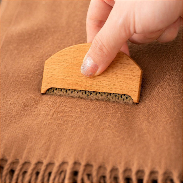 Clothes fabric shaver with light wood handle and dark bristle head removing fabric shaver lint from tan wool sweater