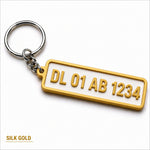 Gold-plated custom number plate keychain with raised lettering on white background for car enthusiasts
