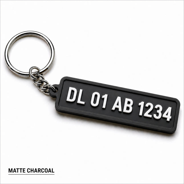 Matte charcoal custom number plate keychain with white raised lettering and silver metal ring for car enthusiasts