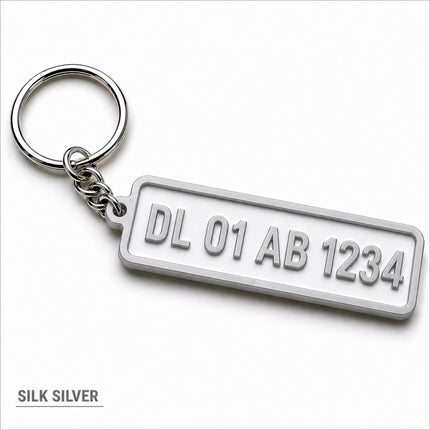 Silver metallic custom number plate keychain with raised lettering personalized for car enthusiasts