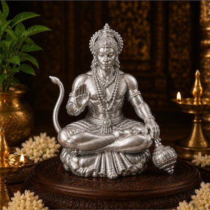 Silver hanuman ji idol in a meditative pose with intricate detailing seated on an ornate wooden base for home temple use