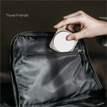 A sleek circular white wireless charging stand with metallic edges from momax q2.mag go 3-in-1 foldable charger