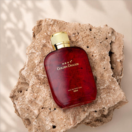 Deep red glass bottle of next golden dragon perfume with a gold-toned ribbed cap for skin care luxury scent
