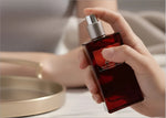 A sleek rectangular bottle of deep red next z plus eau de perfume with a silver nozzle for korean skin care use