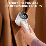 White handheld rechargeable fabric shaver with LED display showing 100 percent humidity for lint remover use