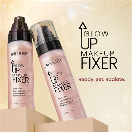 Two translucent pink bottles of swiss beauty glow up makeup fixer with black spray nozzles on a beige pedestal