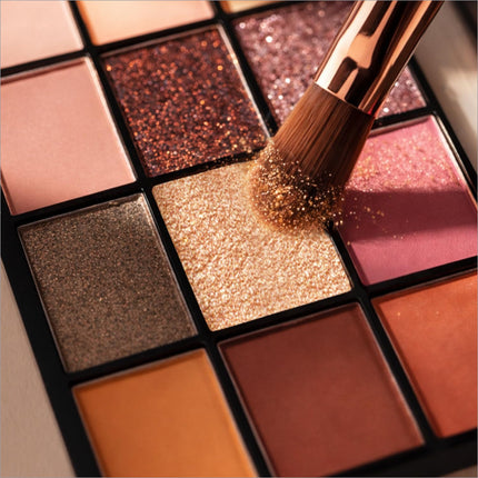 A rose gold makeup brush applying shimmering bronze shade from swiss beauty limitless eyeshadow palette stargaze