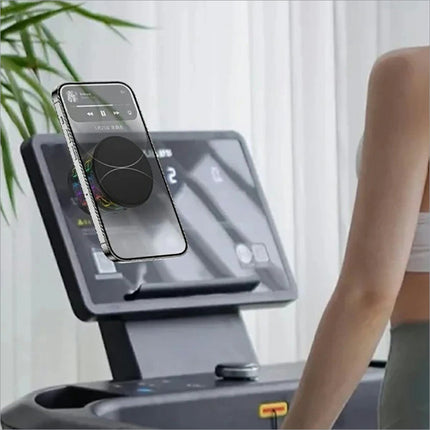 A sleek black smartphone with a silver frame and circular magnetic grip on treadmill console for x12 magnetic car dashboard use